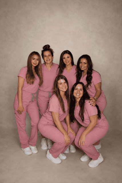 Six women in pink medical scrubs smiling