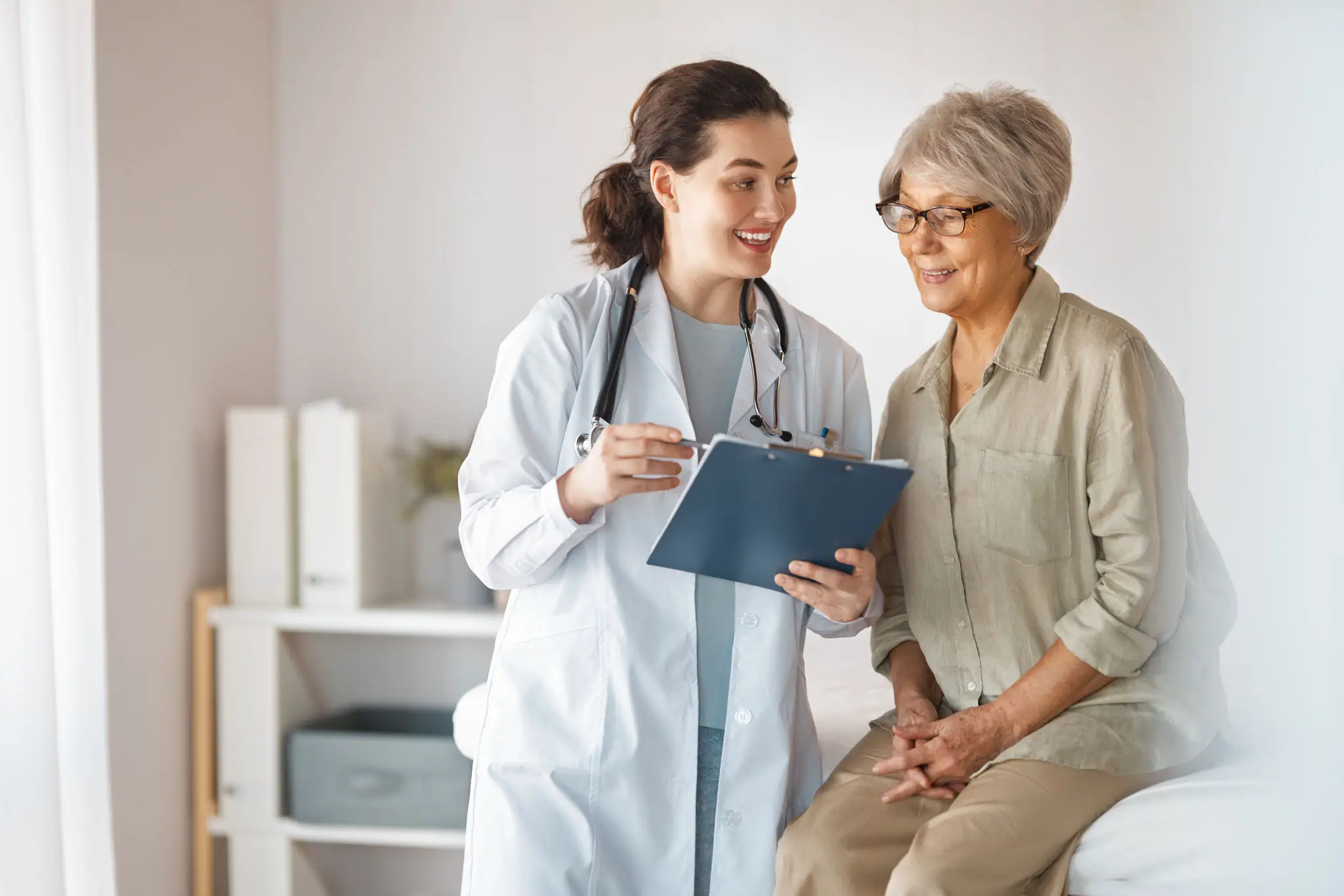 Female doctor consulting senior woman on exam table
