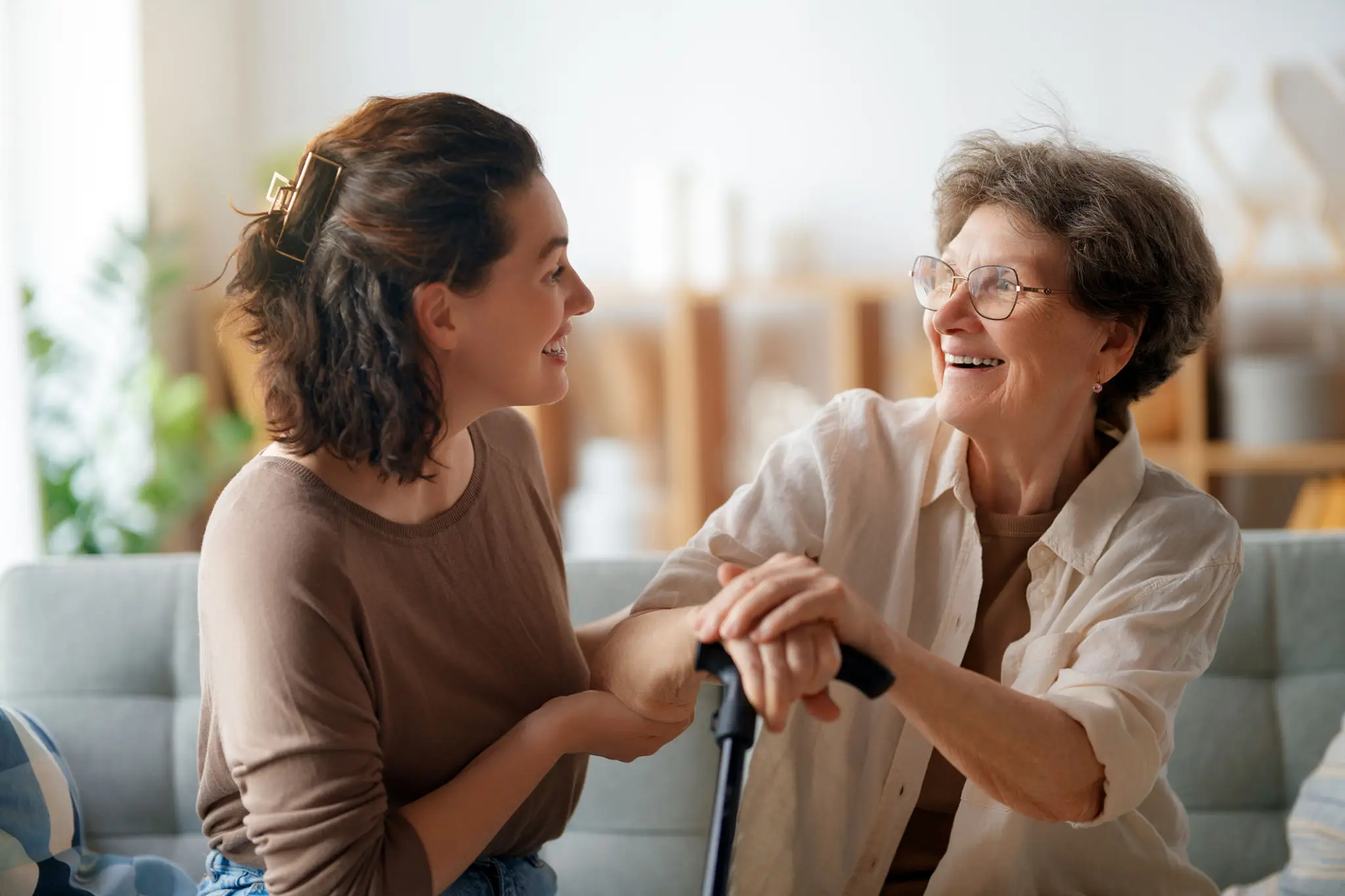 Young woman caring for elderly woman with cane